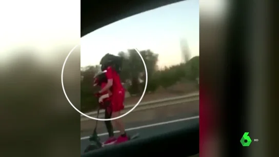 Pareja circulando en una autovía con un patinete eléctrico Pareja circulando en una autovía con un patinete eléctrico
