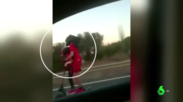 Pareja circulando en una autovía con un patinete eléctrico