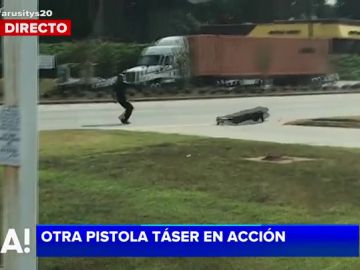 Un policía dispara a un delincuente con una pistola taser Un policía dispara a un delincuente con una pistola taser