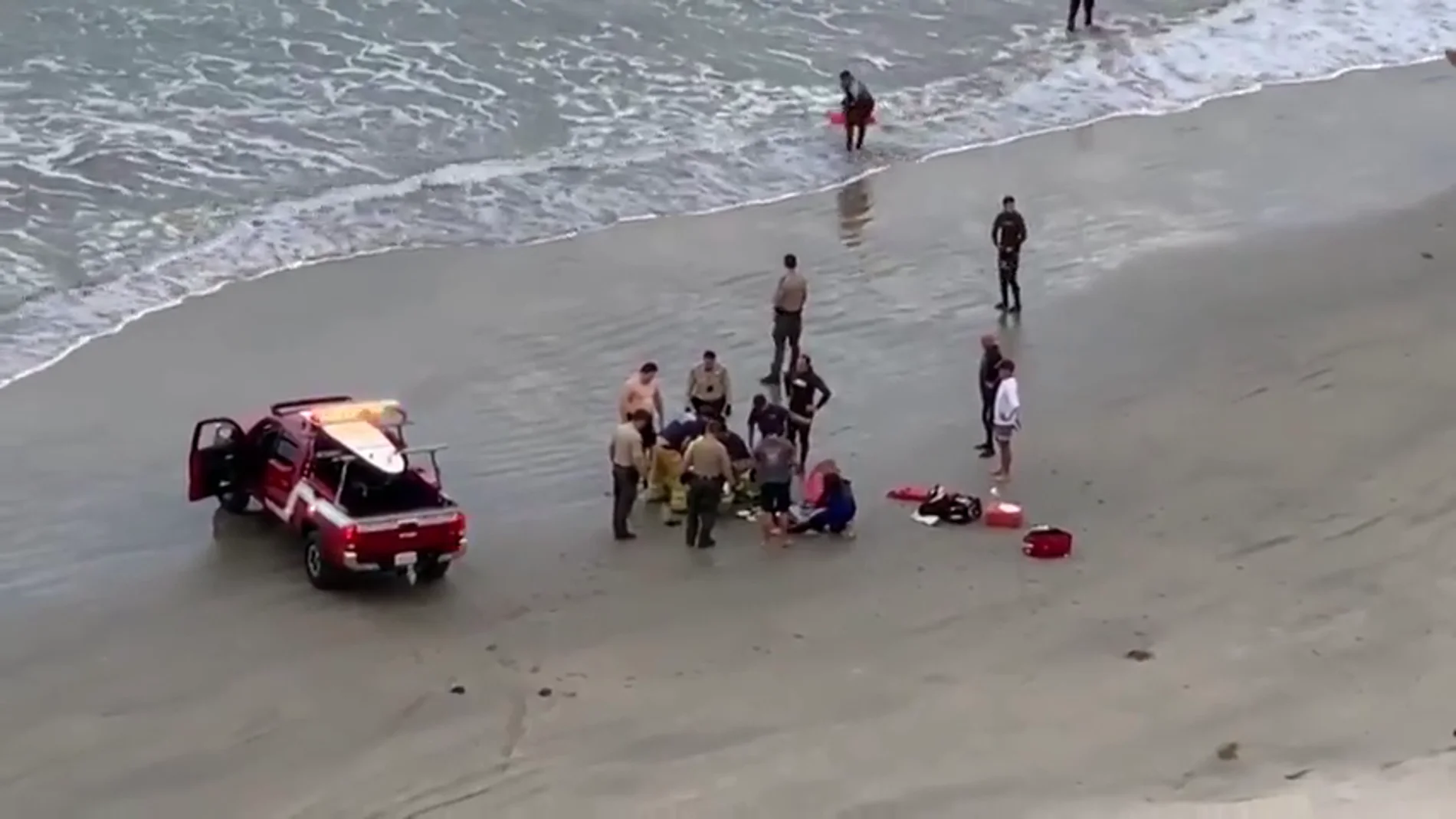 Imagen del momento en el que efectivos sanitarios atienden a un menor atacado por un tiburón en California