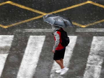 Una persona se protege de la lluvia con un paraguas Una persona se protege de la lluvia con un paraguas