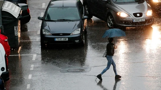 Media España en alerta naranja y amarilla por viento y lluvia Imagen de una persona que se protege con un paraguas de la lluvia