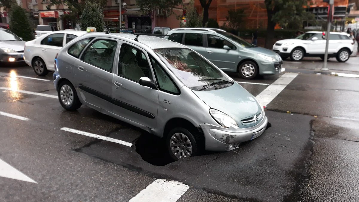 Un coche queda encajado en un socavón en Madrid Un coche queda encajado en un socavón en Madrid