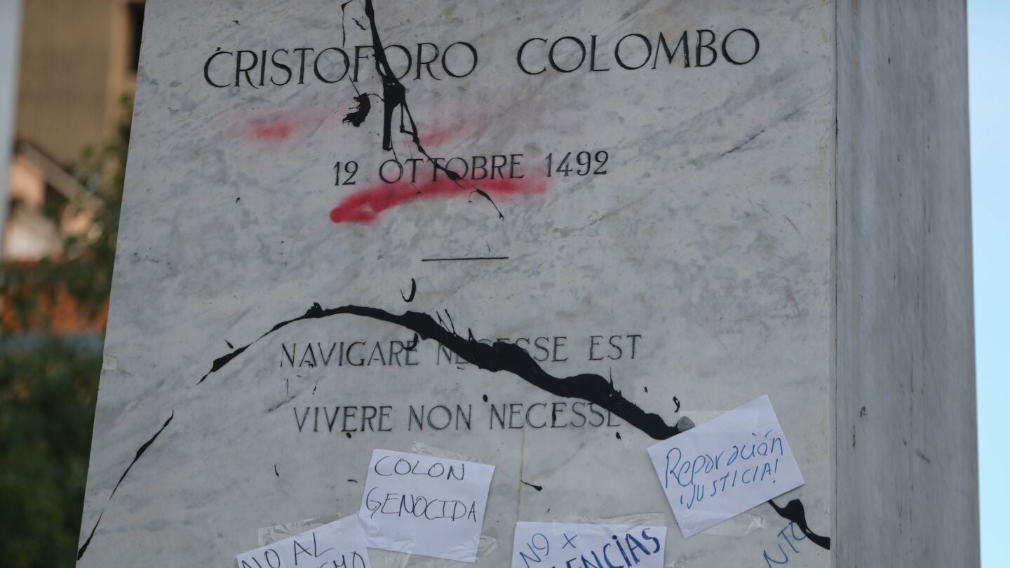  Imagen de la pintura arrojada y de los carteles pegados a la estatua de Crist&oacute;bal Col&oacute;n