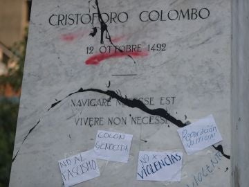 Imagen de la pintura arrojada y de los carteles pegados a la estatua de Cristóbal Colón Imagen de la pintura arrojada y de los carteles pegados a la estatua de Cristóbal Colón