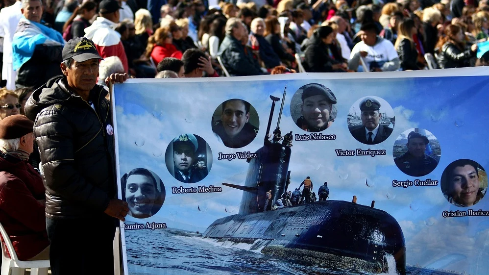 Imagen de un hombre que sostiene una pancarta con imágenes de algunos tripulantes del submarino argentino ARA San Juan