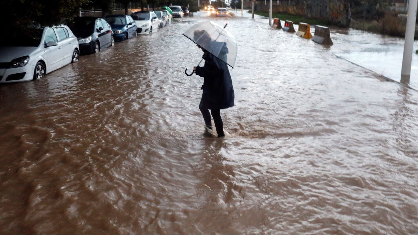 Una persona cruza una calle inundada durante el temporal en Valencia
