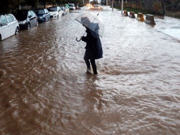 Una persona cruza una calle inundada durante el temporal en Valencia Una persona cruza una calle inundada durante el temporal en Valencia