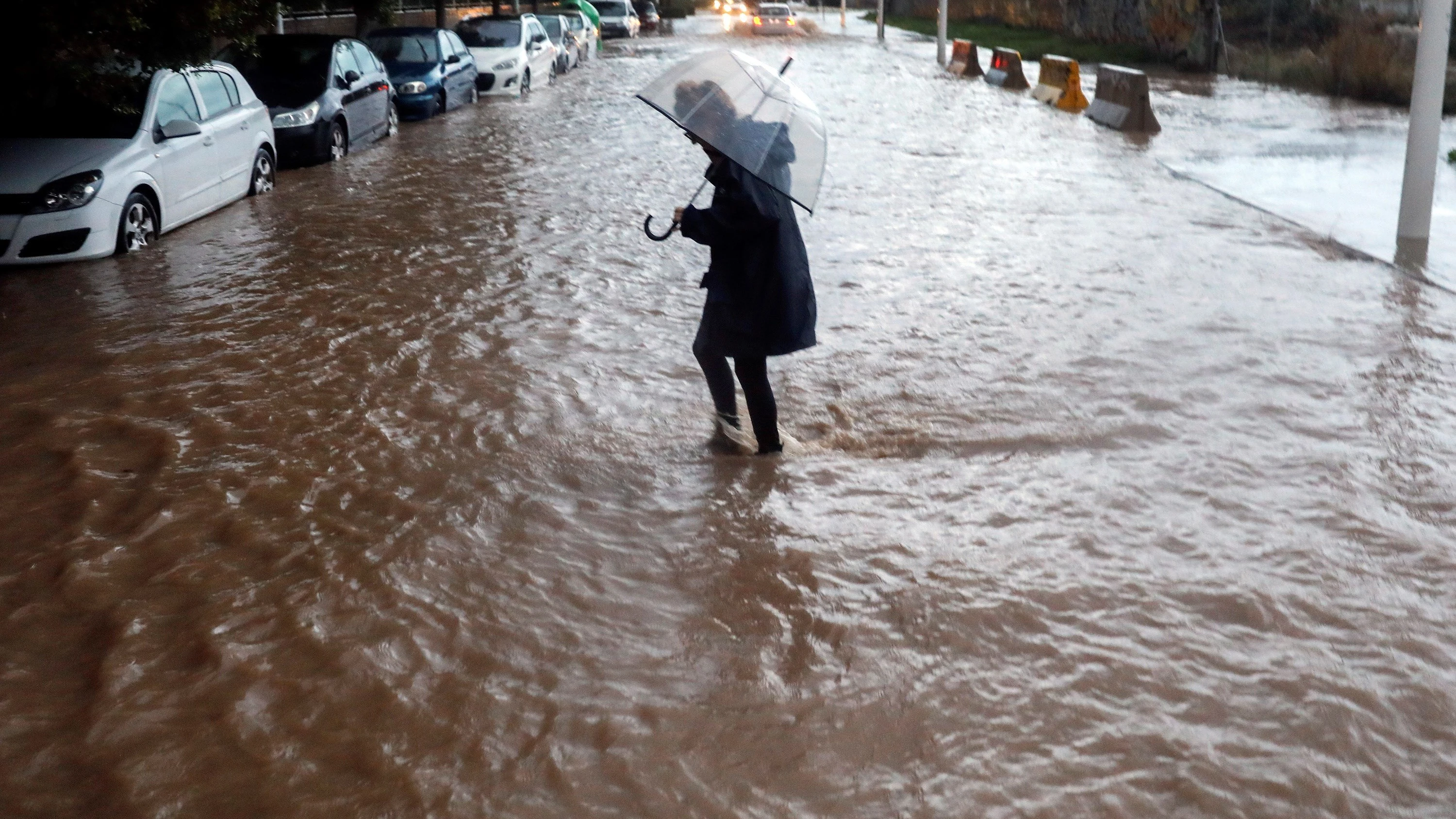 Una persona cruza una calle inundada durante el temporal en Valencia