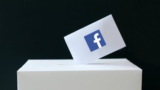 Papeleta con el s&iacute;mbolo de Facebook siendo depositada en una urna de votaciones