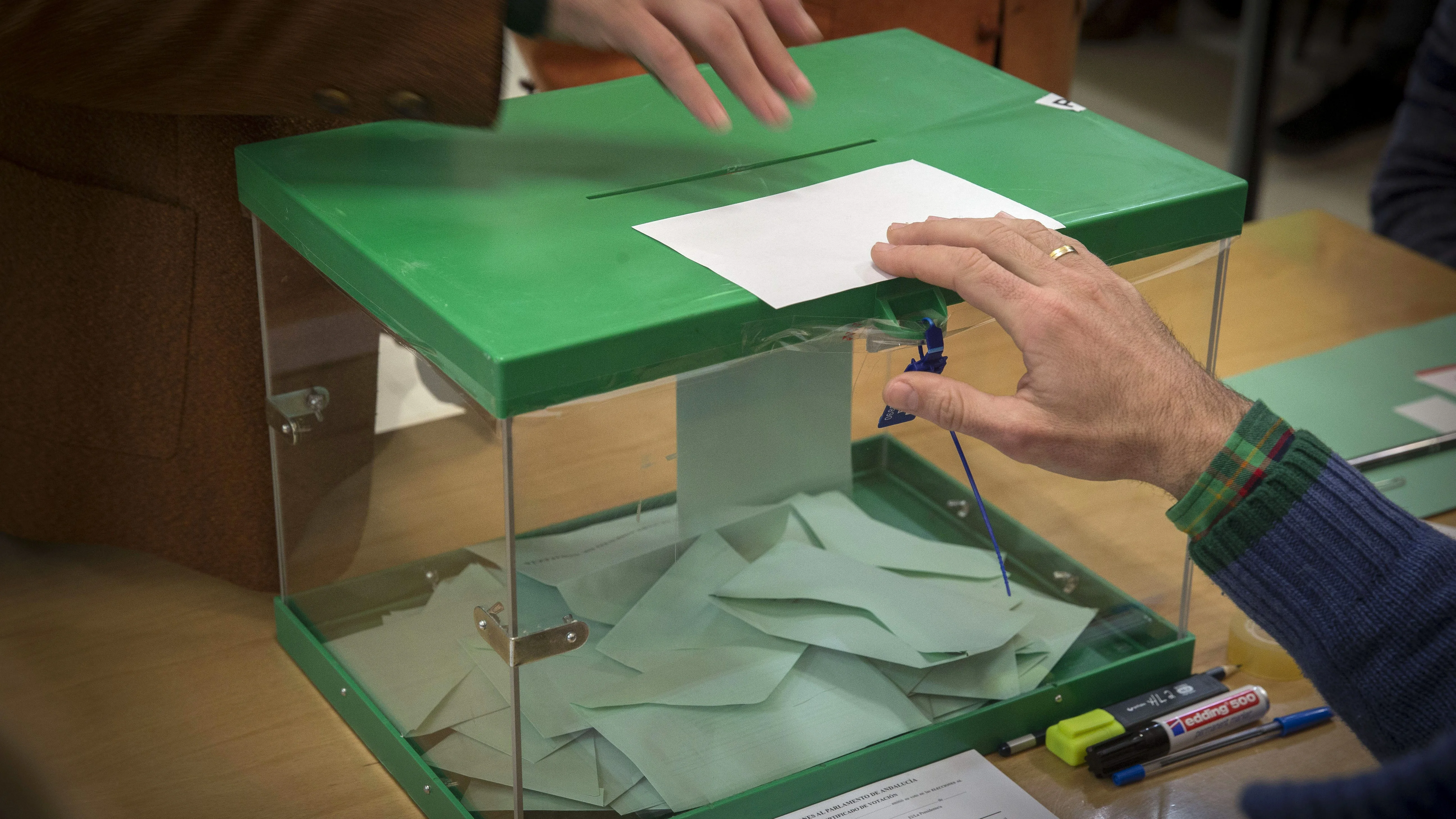 Un votante ejerce su derecho introduciendo la papeleta en la urna en un colegio electoral en Sevilla 