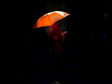 Una persona se protege del sol con un paraguas Una persona se protege del sol con un paraguas
