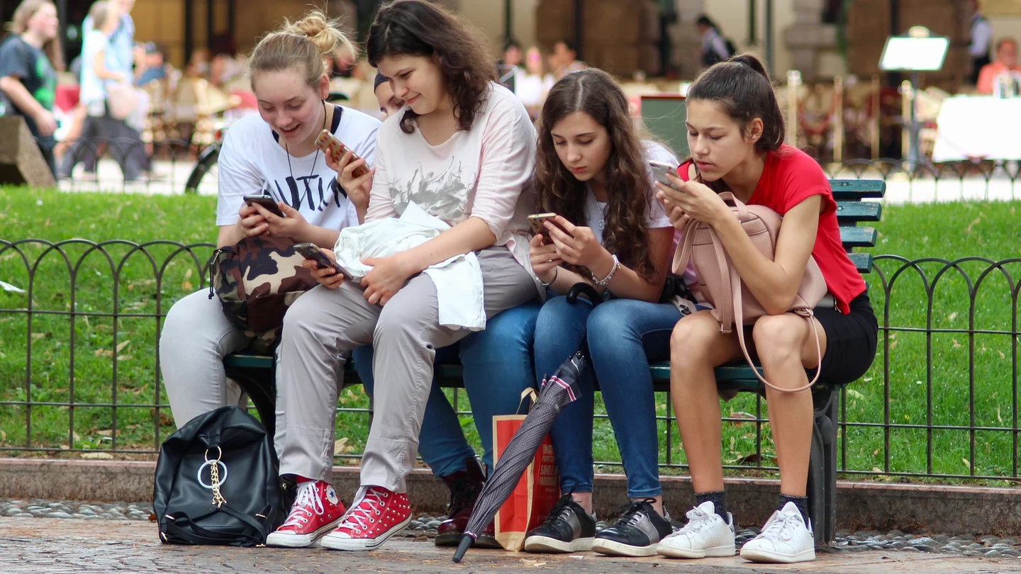 Jóvenes consultando sus móviles. Aunque menos que los adolescentes, los padres también presentan dependencia del móvil.