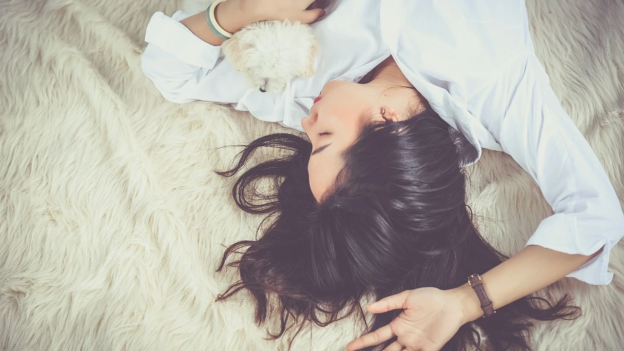 mujer durmiendo en una cama con un perro