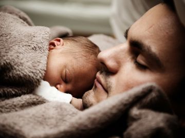 Un padre dormido junto a su bebé Un padre dormido junto a su bebé