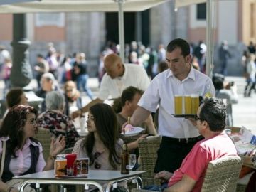Un camarero atiende la mesa de una terraza. Un camarero atiende la mesa de una terraza.
