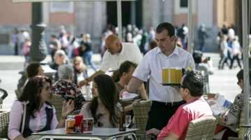 Un camarero atiende la mesa de una terraza.