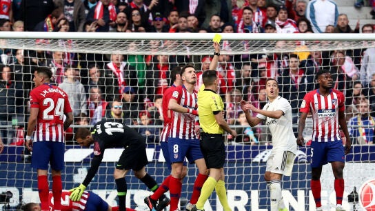 Estrada Fern&aacute;ndez muestra una tarjeta amarilla durante el Atl&eacute;tico-Real Madrid