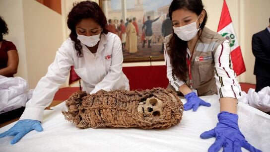 Dos mujeres junto a una momia de un ni&ntilde;o de origen aimara