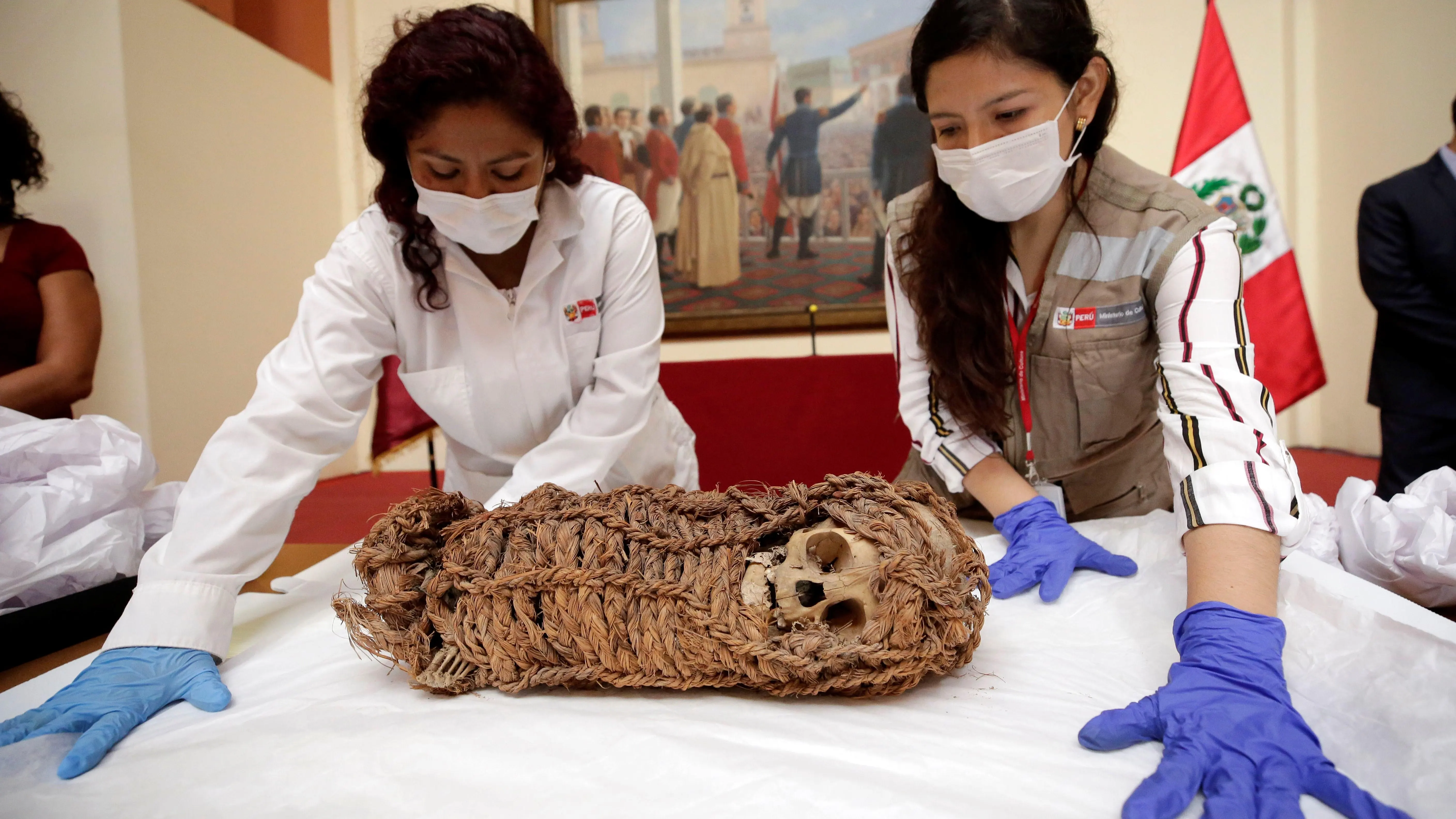 Dos mujeres junto a una momia de un niño de origen aimara