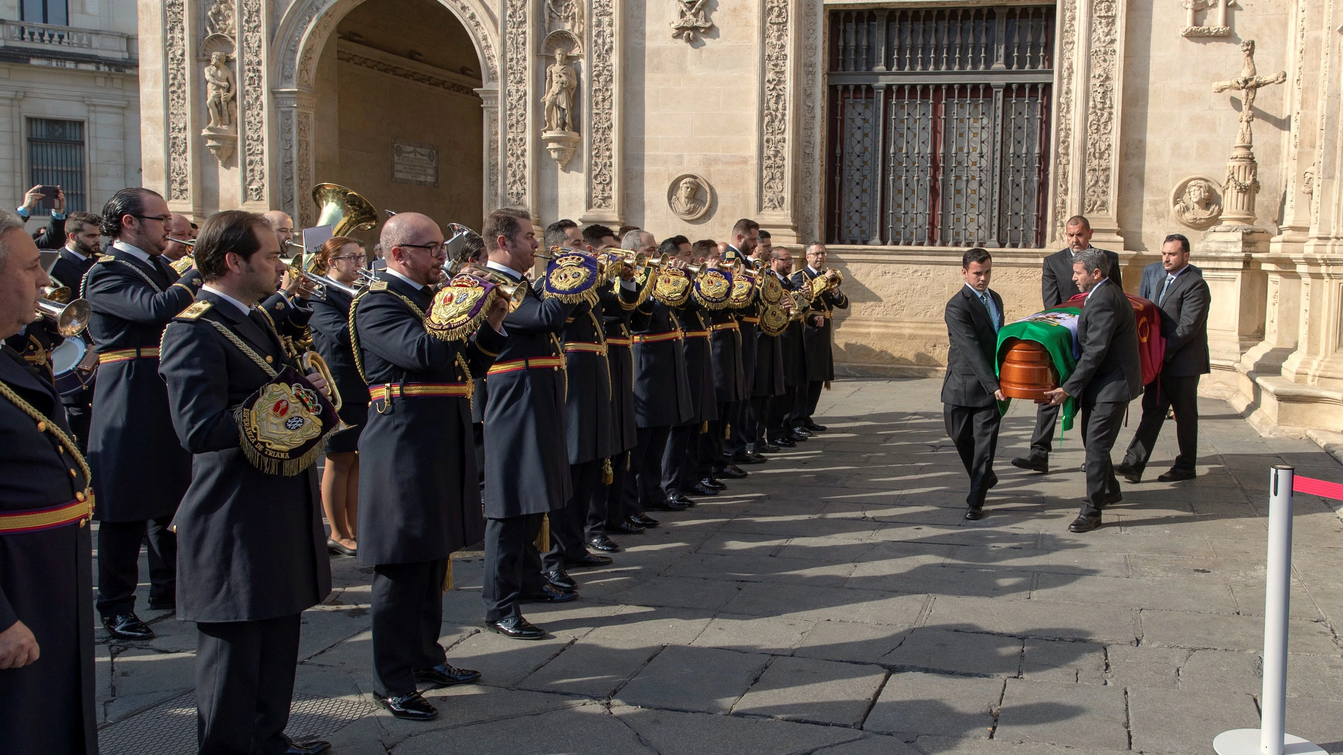 La banda de música de la Hermandad de las Tres Caídas tocando ante el Ayuntamiento de Sevilla para dar el último adiós al dramaturgo Salvador Távora