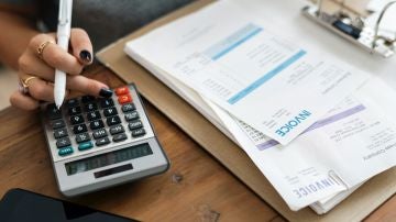 Una mujer revisa sus facturas con la ayuda de una calculadora
