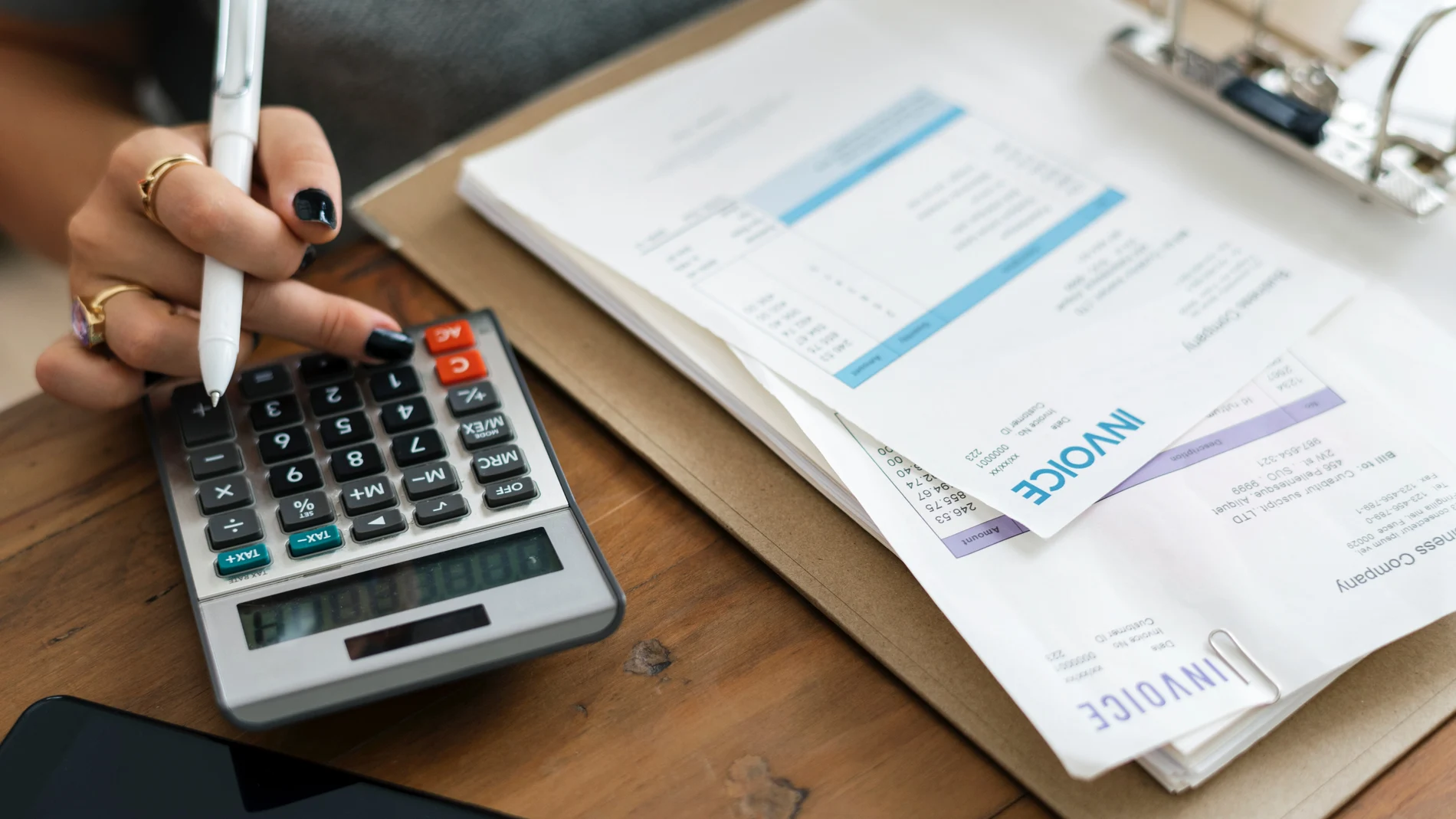 Una mujer revisa sus facturas con la ayuda de una calculadora
