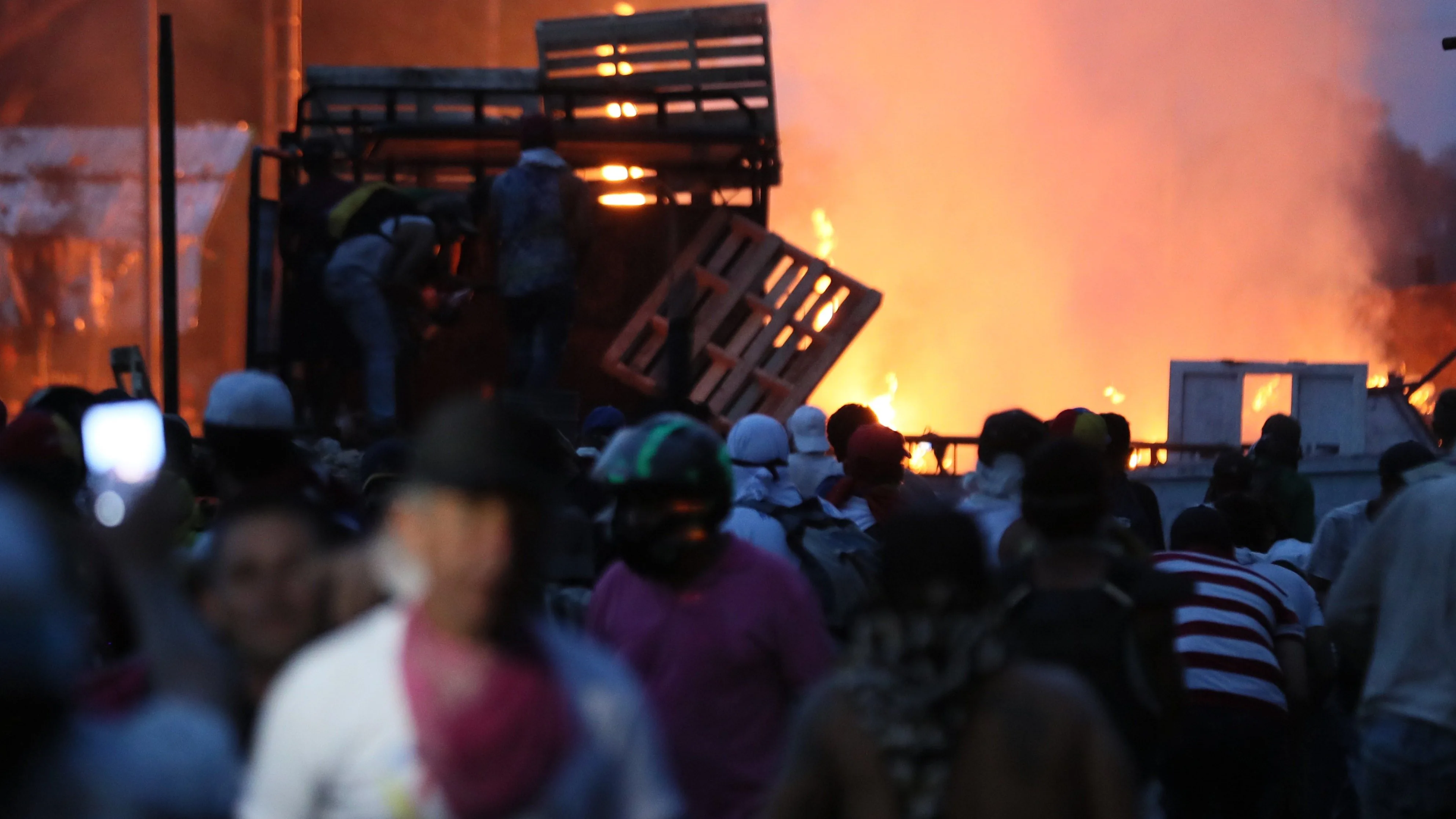 Manifestantes se enfrentan con miembros de la Policía Nacional Bolivariana, junto a un camión que transportaba ayuda humanitaria y fue quemado.