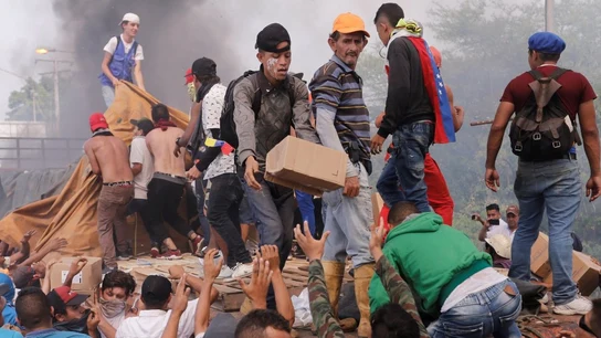 Personas intentan sacar parte de la ayuda humanitaria que se encuentra un camión que fue quemado Personas intentan sacar parte de la ayuda humanitaria que se encuentra un camión que fue quemado