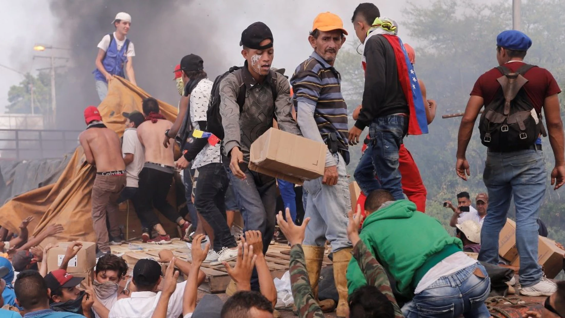 Personas intentan sacar parte de la ayuda humanitaria que se encuentra un camión que fue quemado