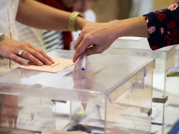 Una mujer deposita su voto en una urna electoral Una mujer deposita su voto en una urna electoral