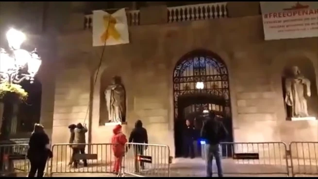 Un grupo de personas retiran el lazo amarillo del Ayuntamiento de Barcelona