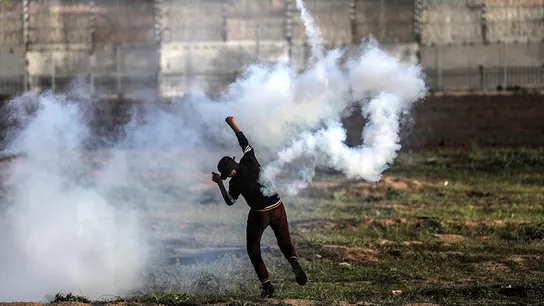 Un palestino devuelve una granada de gas lacrimógeno durante protestas en la frontera entre Israel y Palestina Un palestino devuelve una granada de gas lacrimógeno durante protestas en la frontera entre Israel y Palestina
