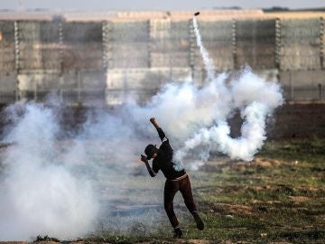 Un palestino devuelve una granada de gas lacrimógeno durante protestas en la frontera entre Israel y Palestina Un palestino devuelve una granada de gas lacrimógeno durante protestas en la frontera entre Israel y Palestina
