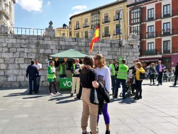 Una pareja de lesbianas se besa frente a un puesto de Vox Una pareja de lesbianas se besa frente a un puesto de Vox