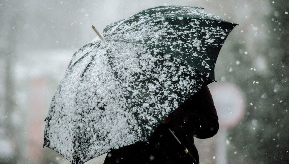 Imagen de archivo de una persona con un paraguas mientras nieva