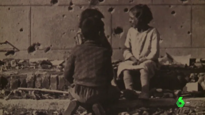 Niños sobre una pared con impactos de Metralla