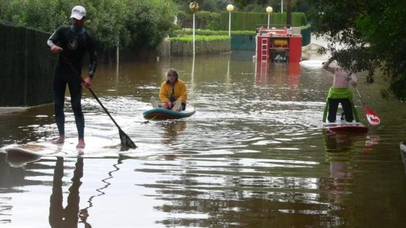 Jacinta es rescatada por sus vecinos subida a una tabla de paddle surf.