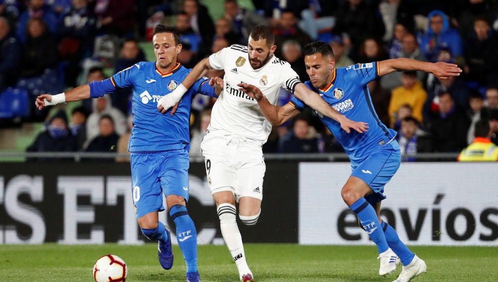Benzema conduce el balón ante la defensa de los jugadores del Getafe