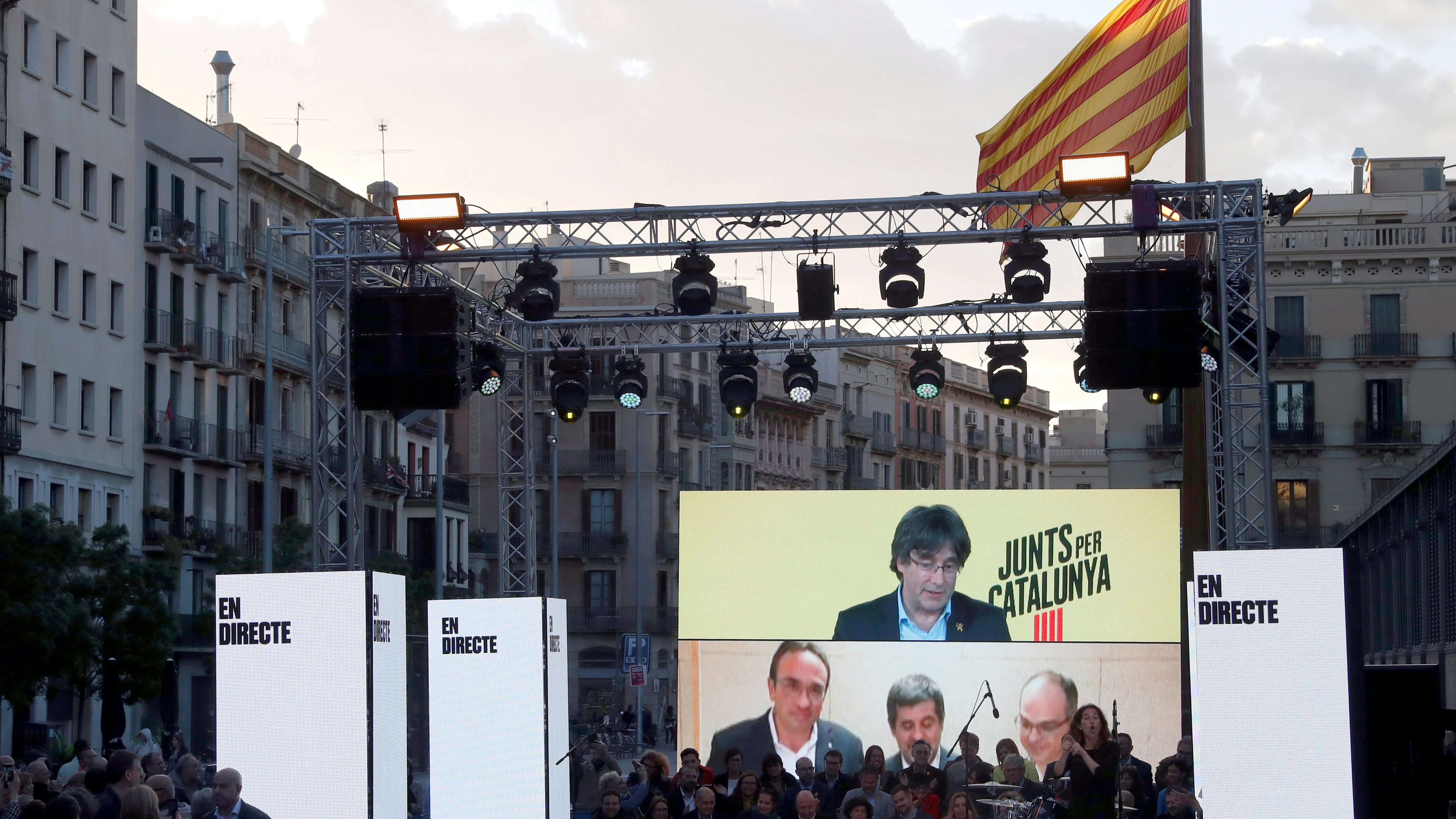 Carles Puigdemont desde Bruselas, y Josep Rull (i) Jordi Sánchez (c) y Jordi Rull (d), desde Soto del Real, intervienen en le acto de final de campaña de JxCat en Barcelona. 