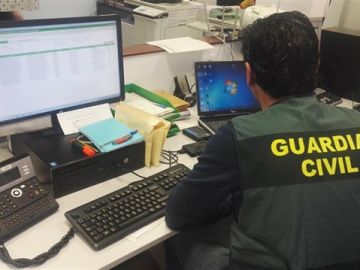 Imagen de archivo de un guardia civil consultando dos ordenadores Imagen de archivo de un guardia civil consultando dos ordenadores