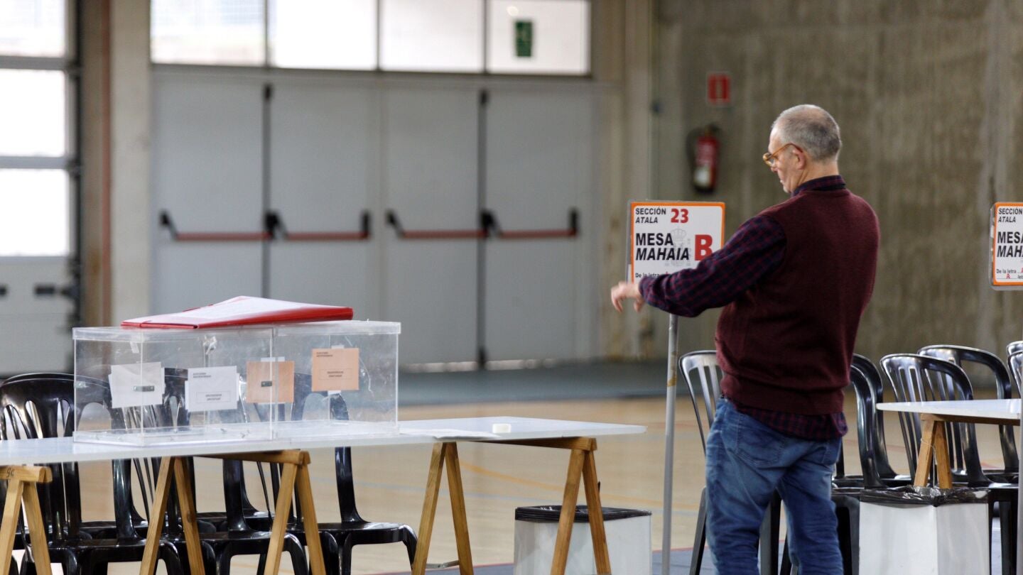 Un funcionario coloca la identificaci&oacute;n de una mesa en un colegio electoral de Vitoria