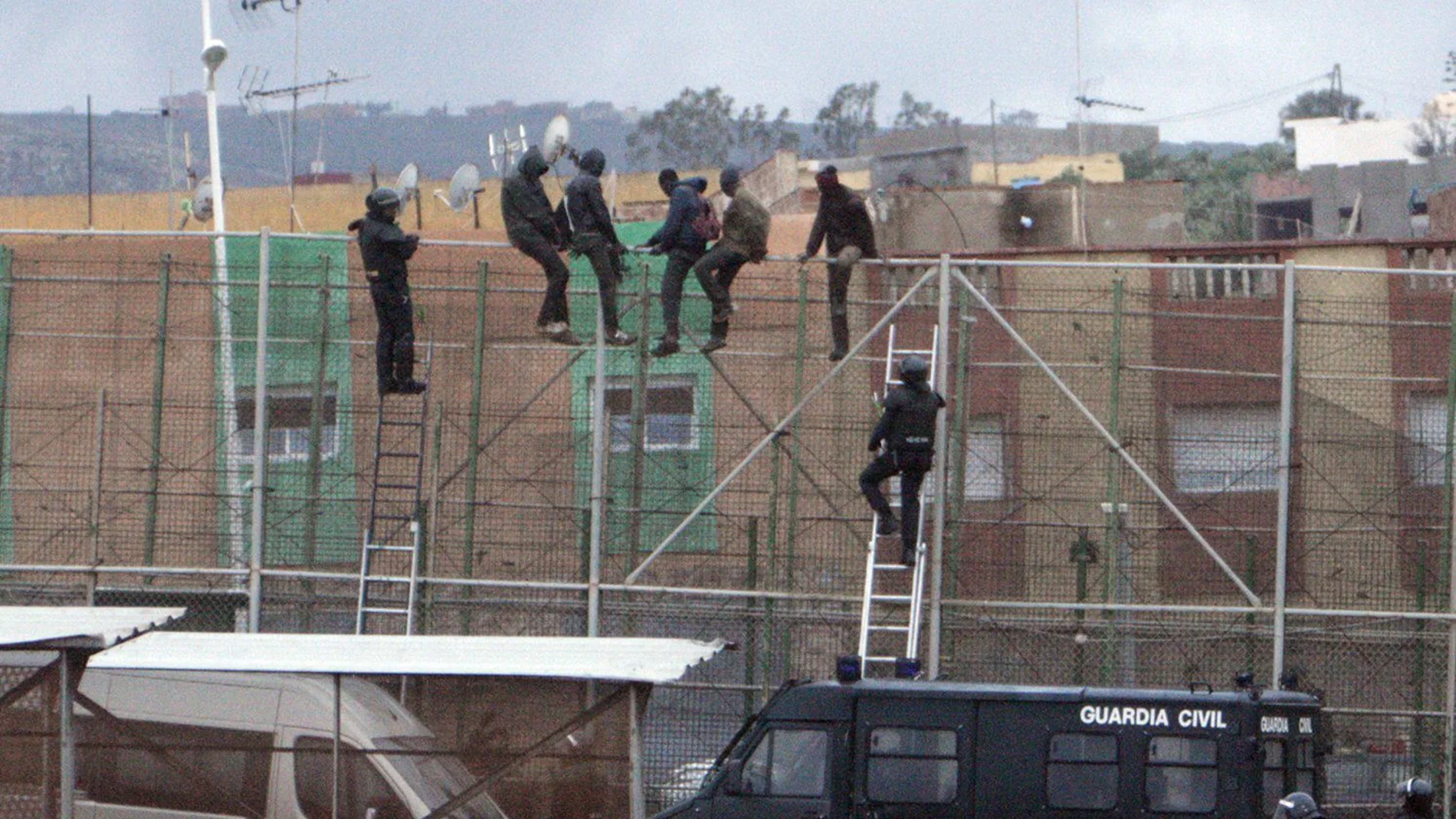 Imagen de archivo de migrantes subidos a la valla de Melilla