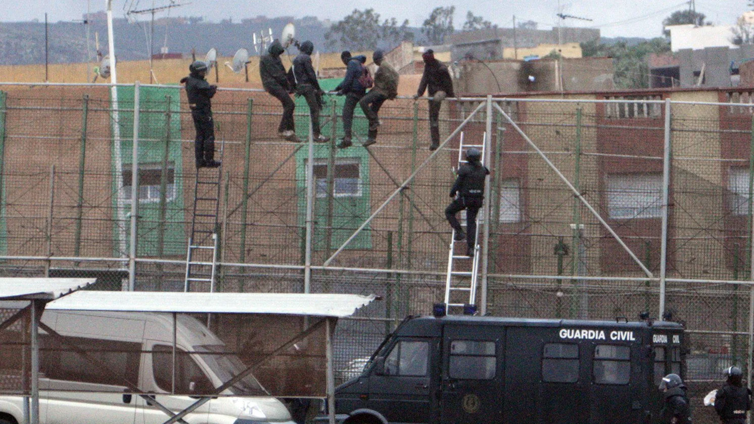 Imagen de archivo de migrantes subidos a la valla de Melilla