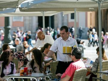 Un camarero sirve bebidas en una terraza en la plaza de la Virgen de Valencia Un camarero sirve bebidas en una terraza en la plaza de la Virgen de Valencia