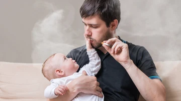 Imagen de archivo de un hombre fumando cerca de un bebé.