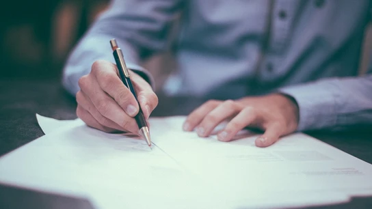 Un hombre escribe en un papel Un hombre escribe en un papel.