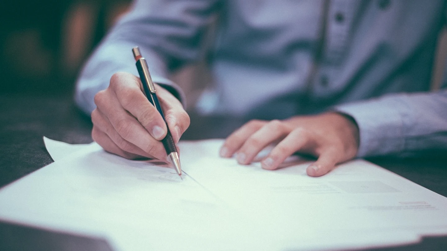 Un hombre escribe en un papel Un hombre escribe en un papel.