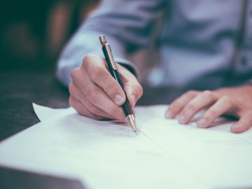 Un hombre escribe en un papel Un hombre escribe en un papel