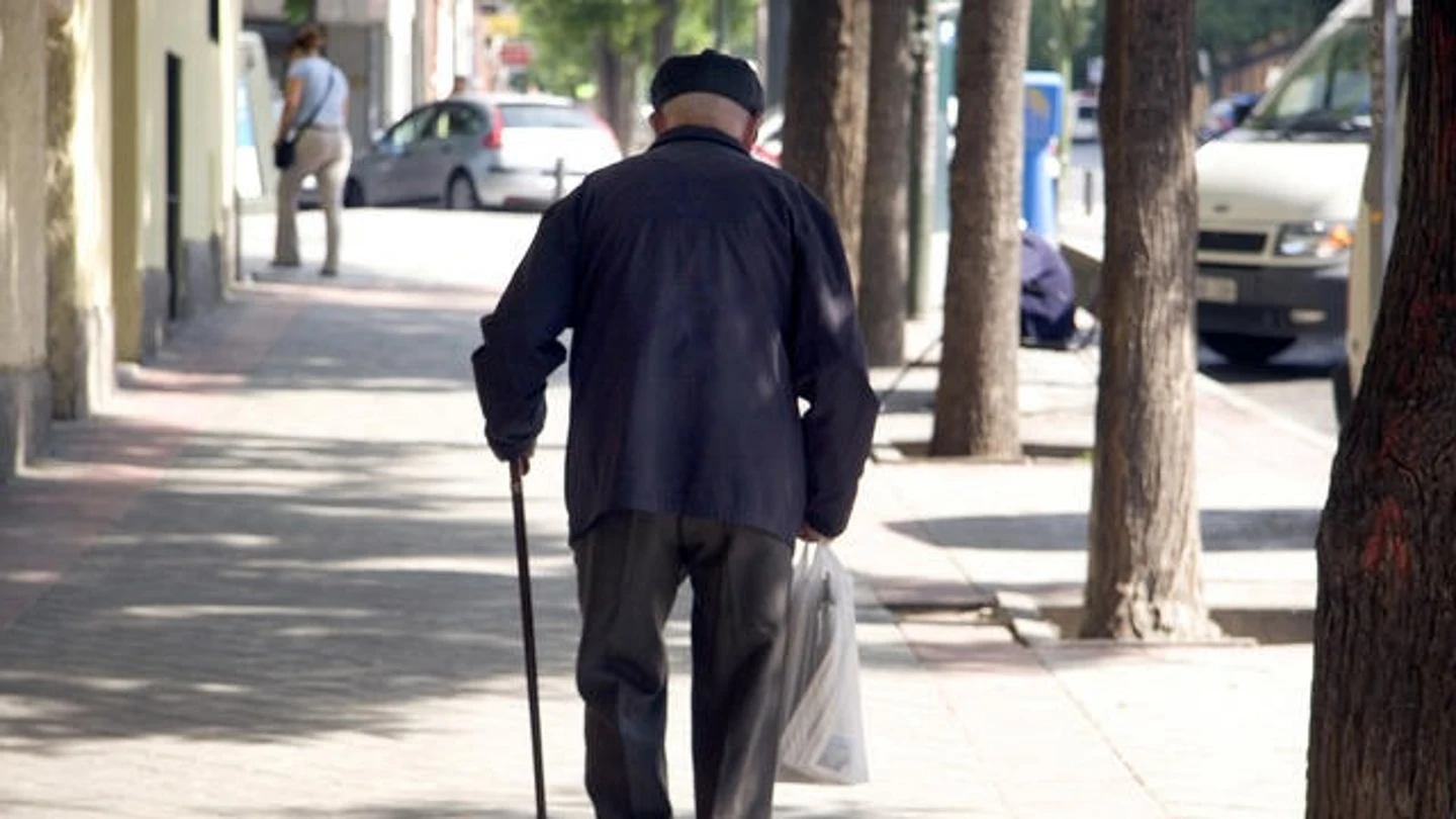 Un jubilado camina en una calle. Un jubilado camina en una calle.